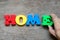 Colorful alphabet in word home with hand hold E to fulfill on wood background Concept of dream home, happy family,