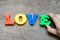 Colorful alphabet in word love with hand hold e letter to fulfill on wood background