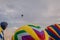 Colorful array of hot air balloons float through the sky at dusk as others prepare to launch