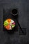 Colorful Asian trendy food, sushi poke bowl with rice, cucumber, salmon, carrot, edamame beans and soy sauce. Top view, close up