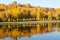 Colorful autumn. Alley along the riverbank on the background of the autumn park. Reflections in the river