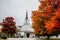 Colorful autumn trees in front of a church with a steeple