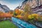 Colorful autumn view of great waterfall in Lauterbrunnen village with azure river.
