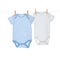 Colorful baby onesies hanging on clothes line against white background