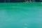 Colorful background emerald green water saturated with radon. Flooded granite quarry.