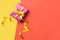 Colorful background with pink gift box. Orange and yellow background with present. Copy space.