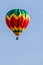 Colorful balloon with a basket flies in a blue sky