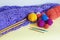 Colorful balls of wools, knitted shawl, knitting needles and crochet hooks. Copy space