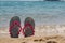 Colorful beach flip flops in a sand near the sea. Woman slippers