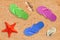 Colorful beach shoes and starfish over sand background