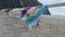 Colorful beach towels hanging on wooden rail swaying in wind on evening beach