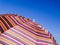 Colorful beach umbrella against the blue sky. Striped texture