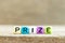 Colorful bead with letter in word prize on wood background
