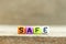 Colorful bead with letter in word safe on wood background
