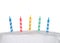 Colorful birthday candles on white frosted cake close up