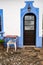 Colorful blue wall facade, door, and table and chairs in the small village of Alte, Portugal