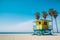 Colorful blue and yellow lifeguard station on beach with palm trees and blue sky, copy space. Generative AI