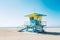 Colorful blue and yellow lifeguard station on beach with palm trees and blue sky, copy space. Generative AI