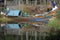 Colorful boat complete with supplies in a pond with reflections.