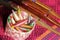 Colorful bobbins in basket and wooden bobbin on silk fabric