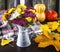 A colorful bouquet of chrysanthemum flowers in a vintage vase, pumpkins, yellow autumn leaves, a woolen scarf.