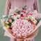 Colorful bouquet of different fresh flowers in the hands of florist woman. Rustic flower background. Craft bouquet of