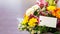 colorful bouquet of various flowers with paper label, blurred background and copy space