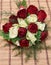 Colorful bouquet of white and red roses on bege bamboo straw mat, close up