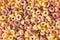 colorful breakfast cereals yellow background top view, rounded breakfast cereal texture
