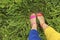 Colorful bright pedicure in different pink and orange sandals and different blue and yellow pants