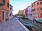 Colorful buildings reflect in the canal on the island of Burano in Italy.