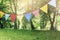 Colorful bunting flags hanging in park. Summer garden party. Outdoor birthday, wedding decoration. Midsummer, festa
