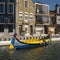 Colorful canal cruise boat with Art Nouveau building in the background in Aveiro, Portugal.