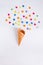 Colorful candies bang from ice cream cone on the white background. Place for lettering. Top view, flat lay.