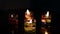 Colorful candles and golden flame reflection on dark surface