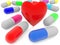 Colorful capsules of medicine and red heart on a white background