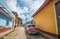 Colorful Caribbean aged village with cobblestone street, classic red car and Colonial house, Cuba, America.