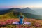 Colorful carpet. The yoga girl in the lotus pose. The lawn with the rhododendron flowers. High mountains. Meditation. Summer.