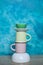 colorful ceramic bowls and coffee cups and teapot on a table against blue background. space for text