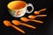 Colorful ceramic cup and orange teaspoons on a dark background