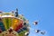 Colorful chain swing carousel in motion at amusement park on blue sky background.