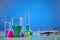 Colorful chemical reagents in beakers, medical flasks, measuring cylinder and phonendoscope, blue background
