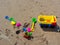 Colorful children`s beach toys on sand background