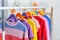 Colorful children`s clothes hanging on wardrobe rack indoors