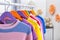 Colorful children`s clothes hanging on wardrobe rack indoors