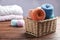 Colorful clews of threads in wicker basket on wooden table