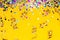 Colorful confetti and golden coiled streamers on yellow background