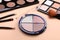 Colorful contouring palettes with brushes on beige background, closeup. Professional cosmetic product