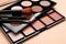 Colorful contouring palettes with brushes on beige background, closeup. Professional cosmetic product