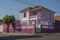 Colorful corner townhouse in an empty street with tree on sidewalk, in a sunny day at San Manuel.